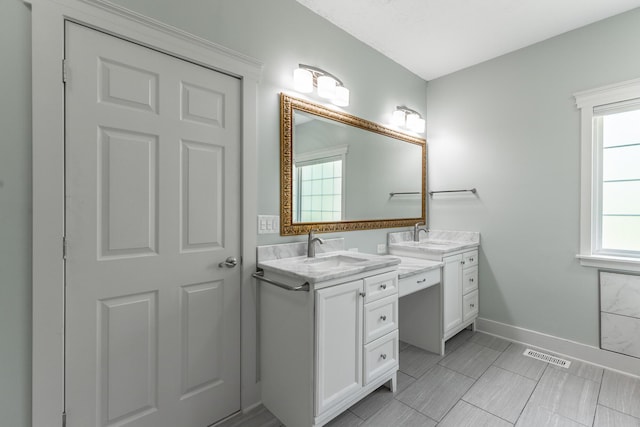 bathroom with baseboards, visible vents, two vanities, and a sink