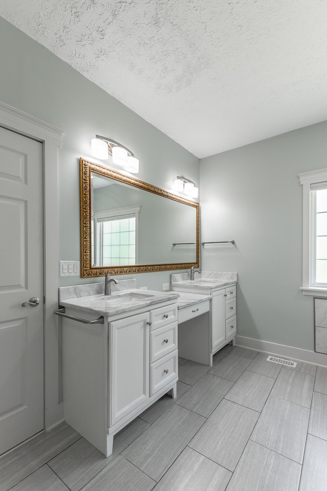 full bath featuring wood finish floors, two vanities, a sink, and visible vents