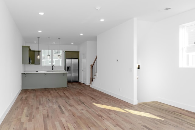943 Montague Pl, Chattanooga, TN 37408 - unfurnished living room featuring recessed lighting, a sink, light wood-style floors, stairs, and baseboards