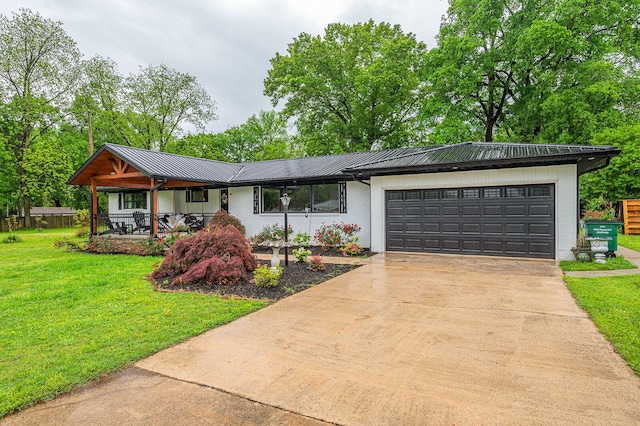 ranch-style house featuring driveway, metal roof, covered porch, a front yard, and a garage