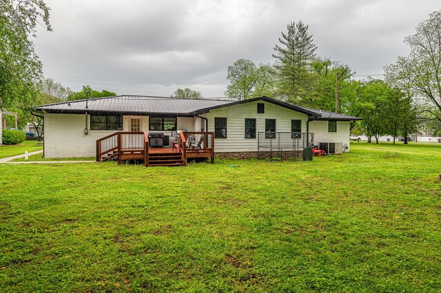 rear view of house with a wooden deck, a yard, and metal roof
