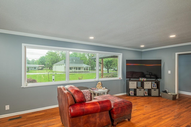living room with ornamental molding, a textured ceiling, wood finished floors, and baseboards