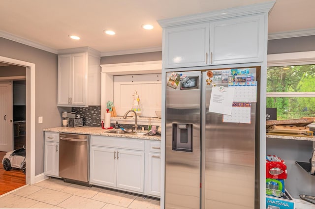 kitchen featuring tasteful backsplash, light stone counters, appliances with stainless steel finishes, a sink, and crown molding