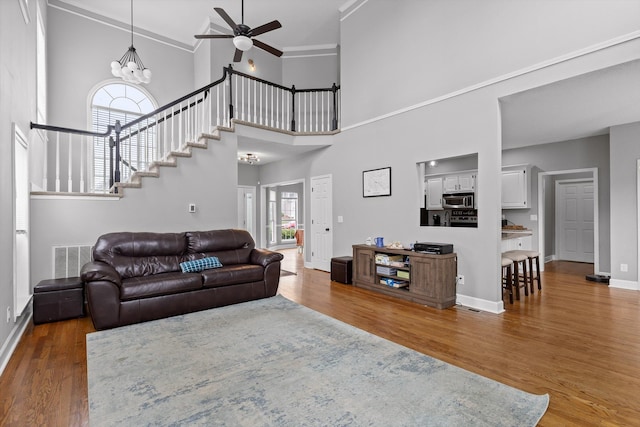 living room with baseboards, ceiling fan with notable chandelier, wood finished floors, and visible vents