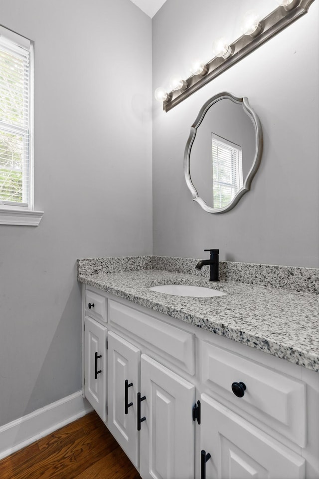 bathroom with baseboards, wood finished floors, and vanity
