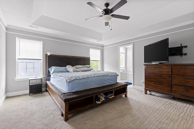 carpeted bedroom featuring visible vents, ensuite bathroom, baseboards, a textured ceiling, and a tray ceiling