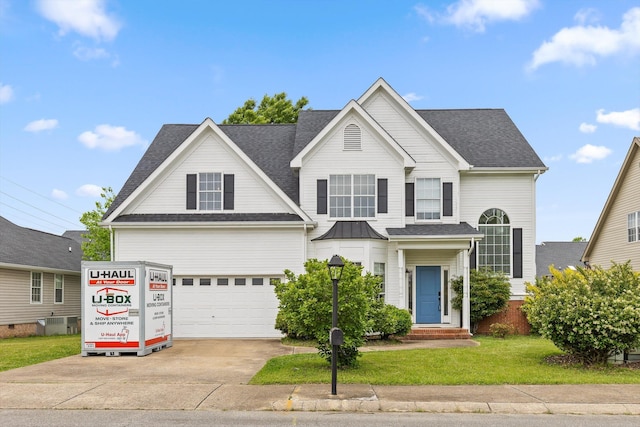 traditional-style home featuring concrete driveway, roof with shingles, a front yard, and a garage