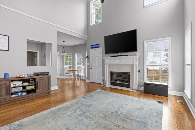 living room with wood finished floors, visible vents, a healthy amount of sunlight, and a towering ceiling