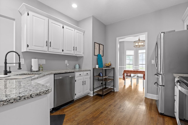 kitchen with a sink, stove, dishwasher, and white cabinetry