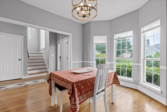 dining room featuring visible vents, wood finished floors, stairway, baseboards, and a chandelier