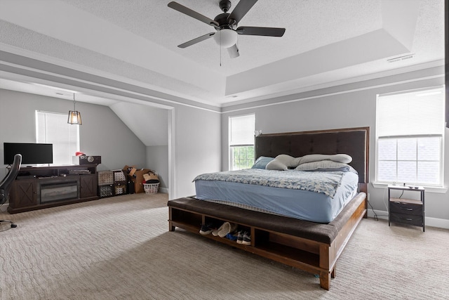 carpeted bedroom featuring a ceiling fan, a textured ceiling, visible vents, vaulted ceiling, and a raised ceiling