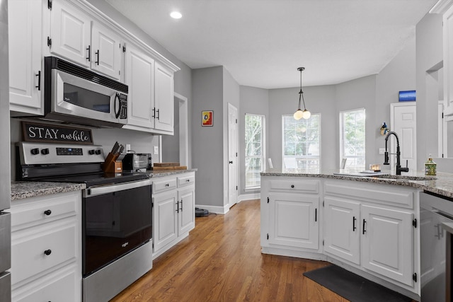 kitchen with a sink, white cabinets, light wood finished floors, stainless steel appliances, and recessed lighting