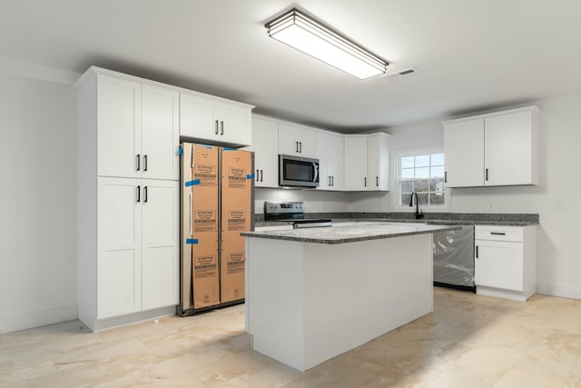 kitchen featuring white cabinetry, dark stone counters, appliances with stainless steel finishes, and a kitchen island