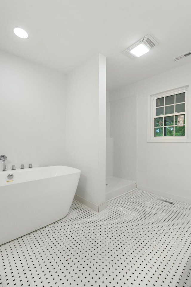 full bath with walk in shower, visible vents, a soaking tub, and baseboards