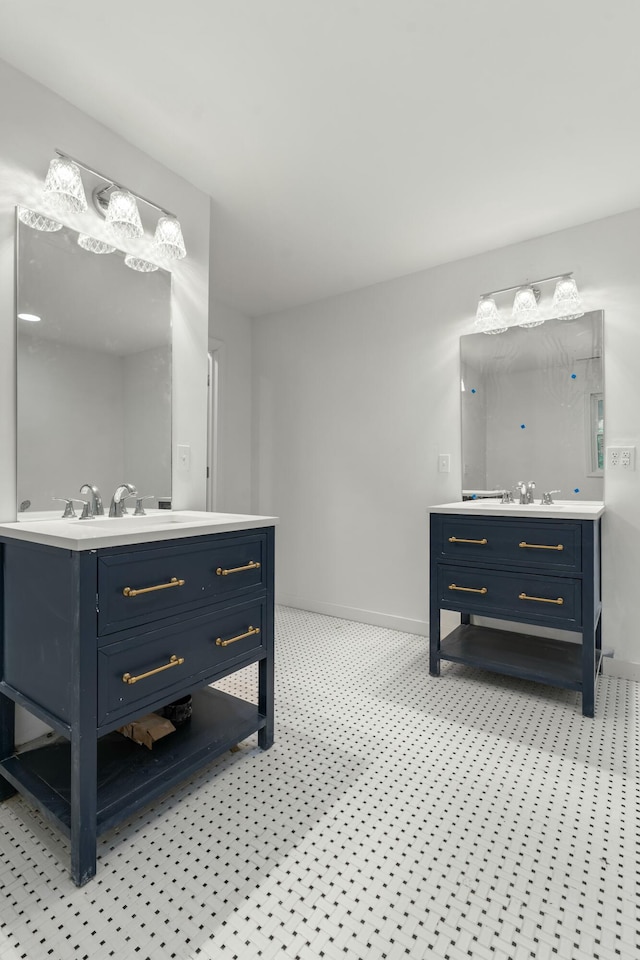full bath with two vanities, a sink, and baseboards