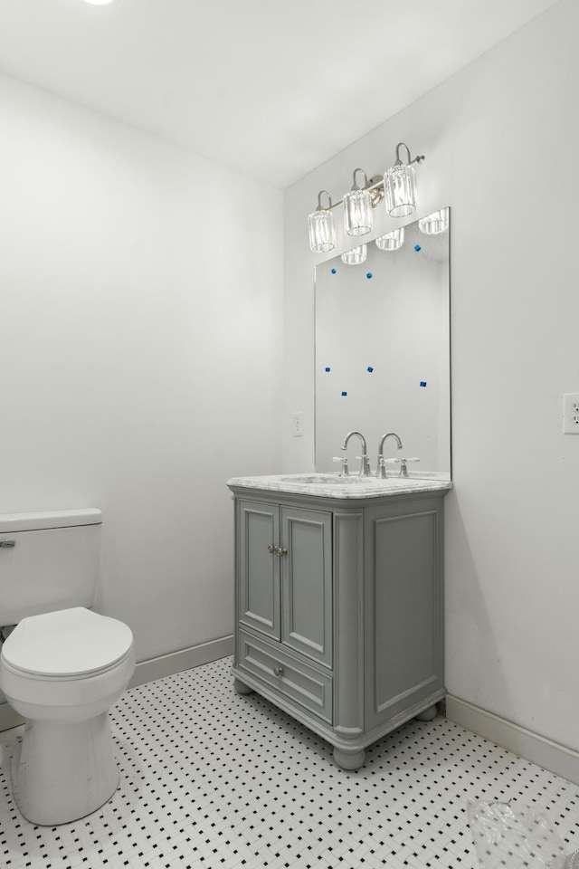 bathroom featuring toilet, vanity, and baseboards
