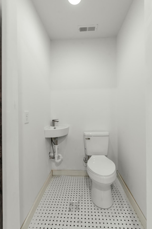 half bathroom featuring tile patterned floors, visible vents, toilet, and baseboards