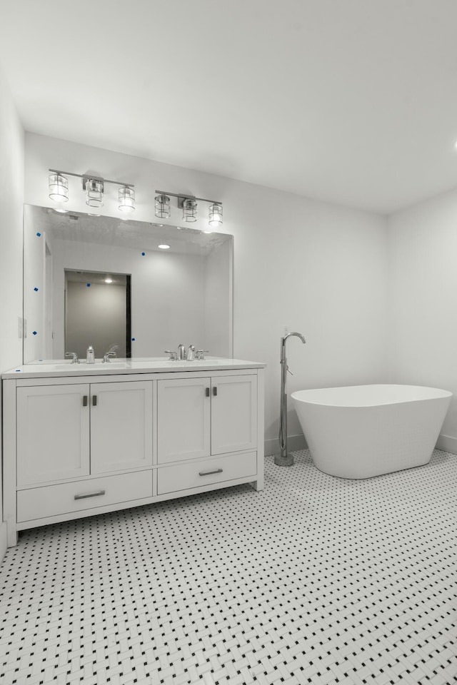 bathroom featuring a sink, double vanity, a freestanding tub, and baseboards