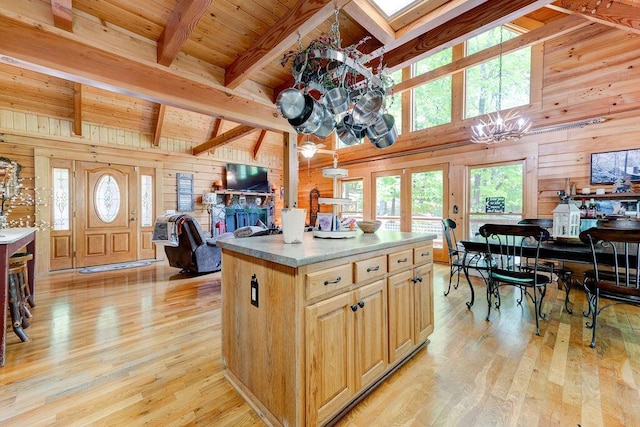 kitchen featuring wooden walls, a center island, an inviting chandelier, and light wood-style flooring