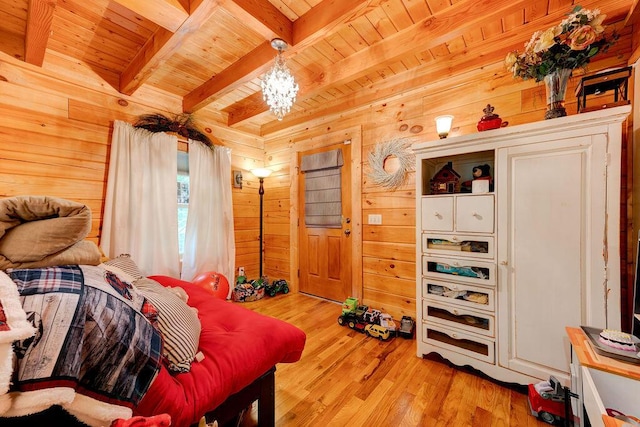 bedroom with a notable chandelier, beam ceiling, wood walls, light wood-style flooring, and wooden ceiling