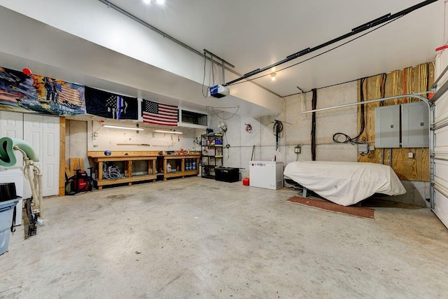 garage with a garage door opener, electric panel, and a workshop area