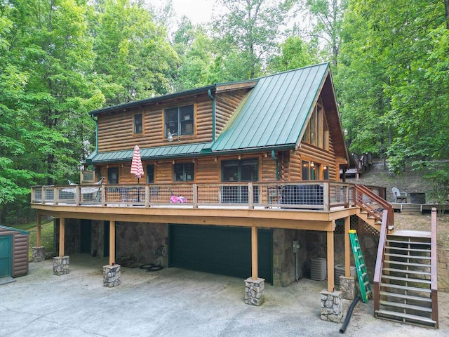 view of front facade with an attached garage, log exterior, stairway, a standing seam roof, and metal roof
