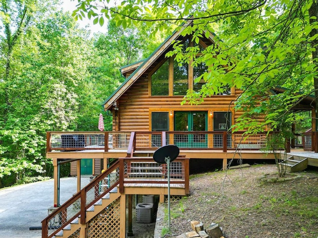 back of house featuring stairs, aphalt driveway, a deck, and log siding