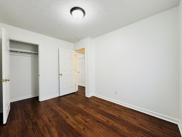 unfurnished bedroom with baseboards, a textured ceiling, dark wood finished floors, and a closet