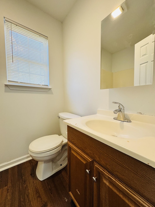 bathroom featuring toilet, baseboards, wood finished floors, and vanity