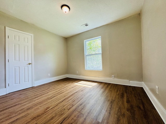spare room featuring visible vents, baseboards, and dark wood-style floors