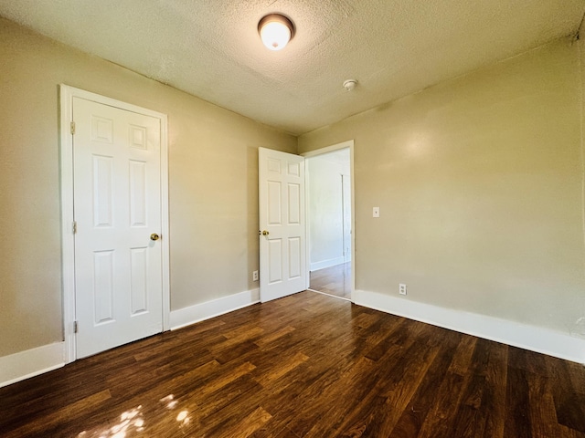unfurnished bedroom featuring baseboards, a textured ceiling, and wood finished floors