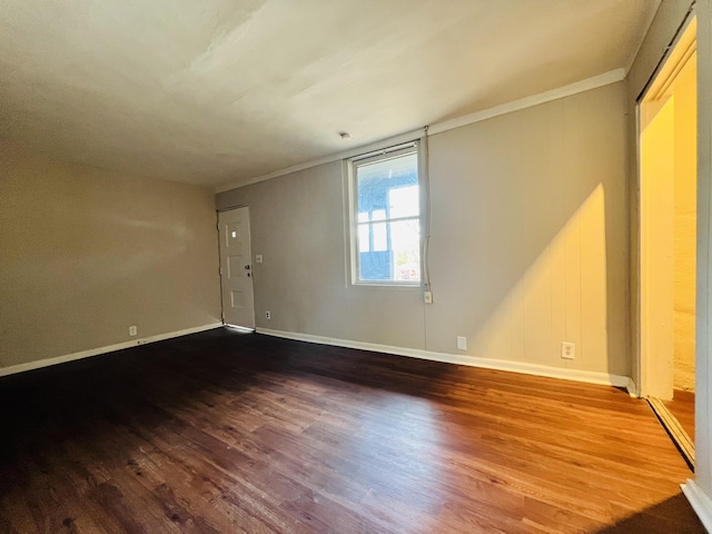 spare room with baseboards, crown molding, and wood finished floors