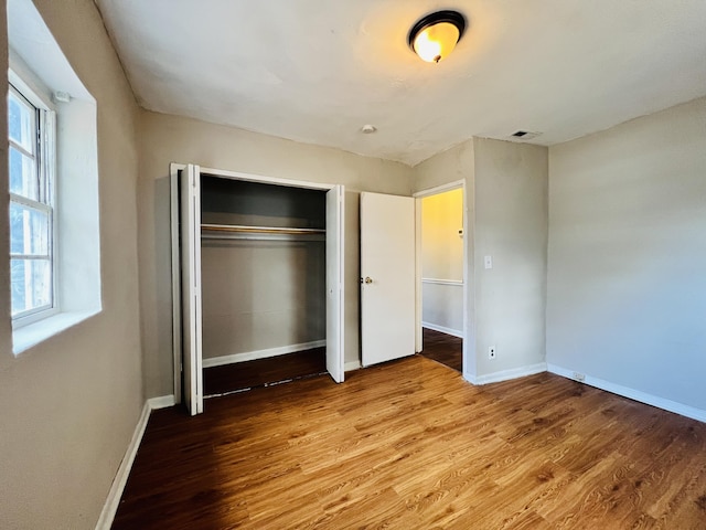 unfurnished bedroom with a closet, baseboards, and wood finished floors