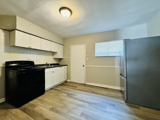 kitchen featuring freestanding refrigerator, light wood-style floors, white cabinets, black electric range, and a sink