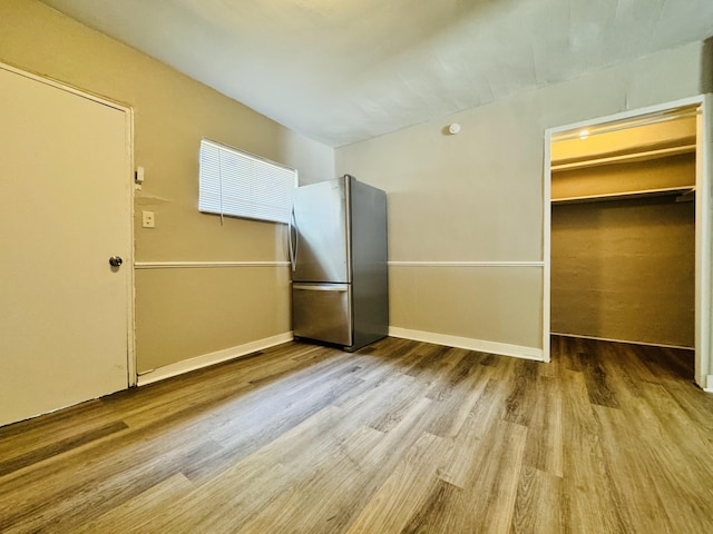 interior space with baseboards, freestanding refrigerator, and wood finished floors