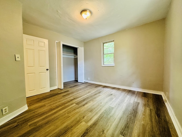 unfurnished bedroom with baseboards, a closet, and wood finished floors