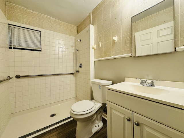 full bath with vanity, a tile shower, toilet, and wood finished floors