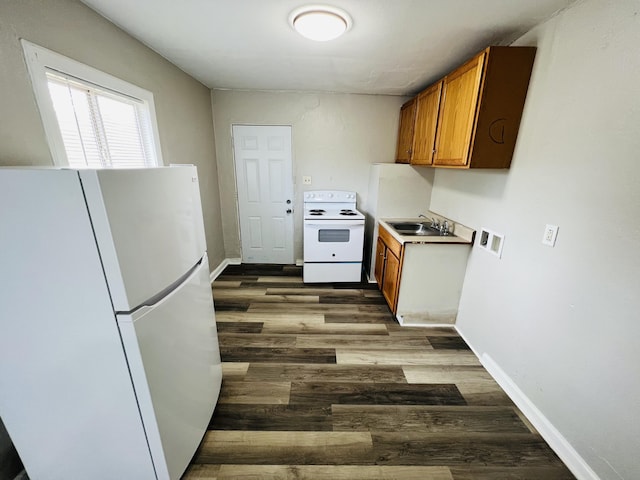 kitchen with a sink, white appliances, brown cabinetry, baseboards, and dark wood-style floors