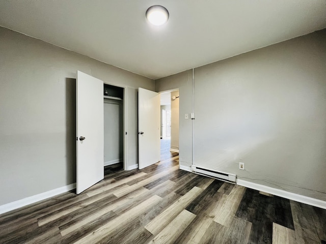 unfurnished bedroom with baseboards, a baseboard radiator, wood finished floors, and a closet