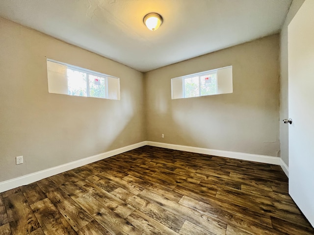 unfurnished room with baseboards and dark wood finished floors