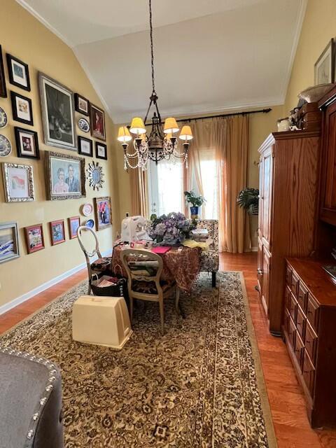 dining area featuring a chandelier, ornamental molding, light wood-style floors, and lofted ceiling