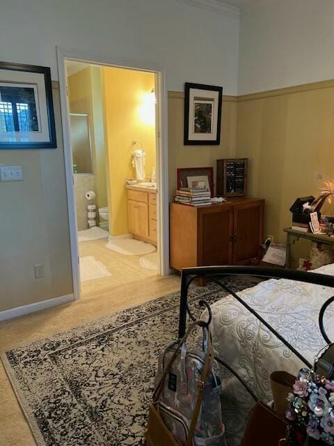 bedroom with ensuite bathroom, ornamental molding, and baseboards