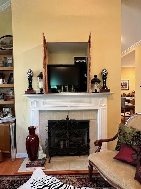 interior space featuring a tile fireplace, wood finished floors, ornamental molding, and built in features