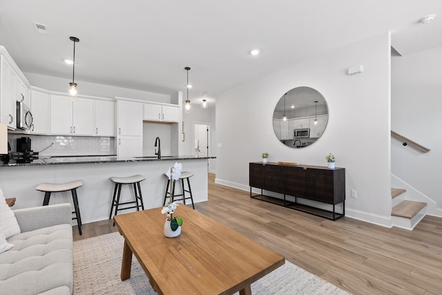 living room featuring recessed lighting, stairway, baseboards, visible vents, and light wood-style floors