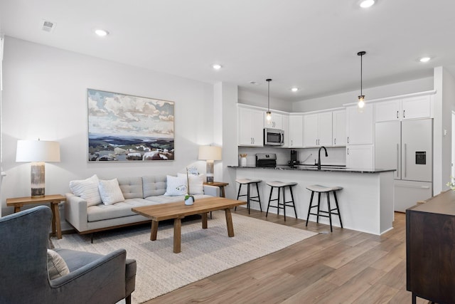 living area with light wood-type flooring, visible vents, and recessed lighting