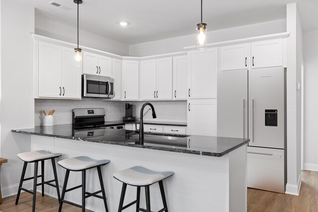 kitchen featuring light wood finished floors, a sink, white cabinets, visible vents, and appliances with stainless steel finishes