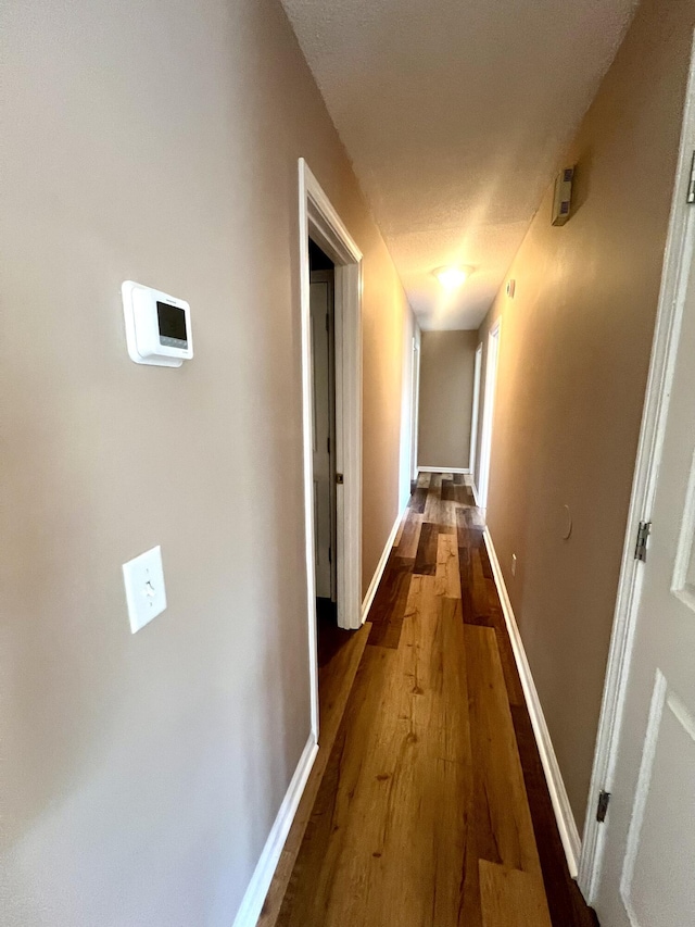 corridor with wood finished floors and baseboards