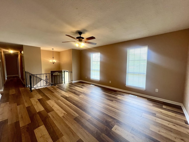 empty room with a textured ceiling, ceiling fan, wood finished floors, and baseboards