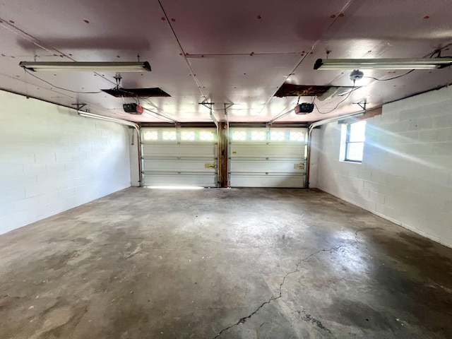 garage featuring a garage door opener and concrete block wall
