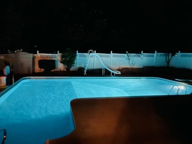 view of pool with a water slide, fence, and a fenced in pool